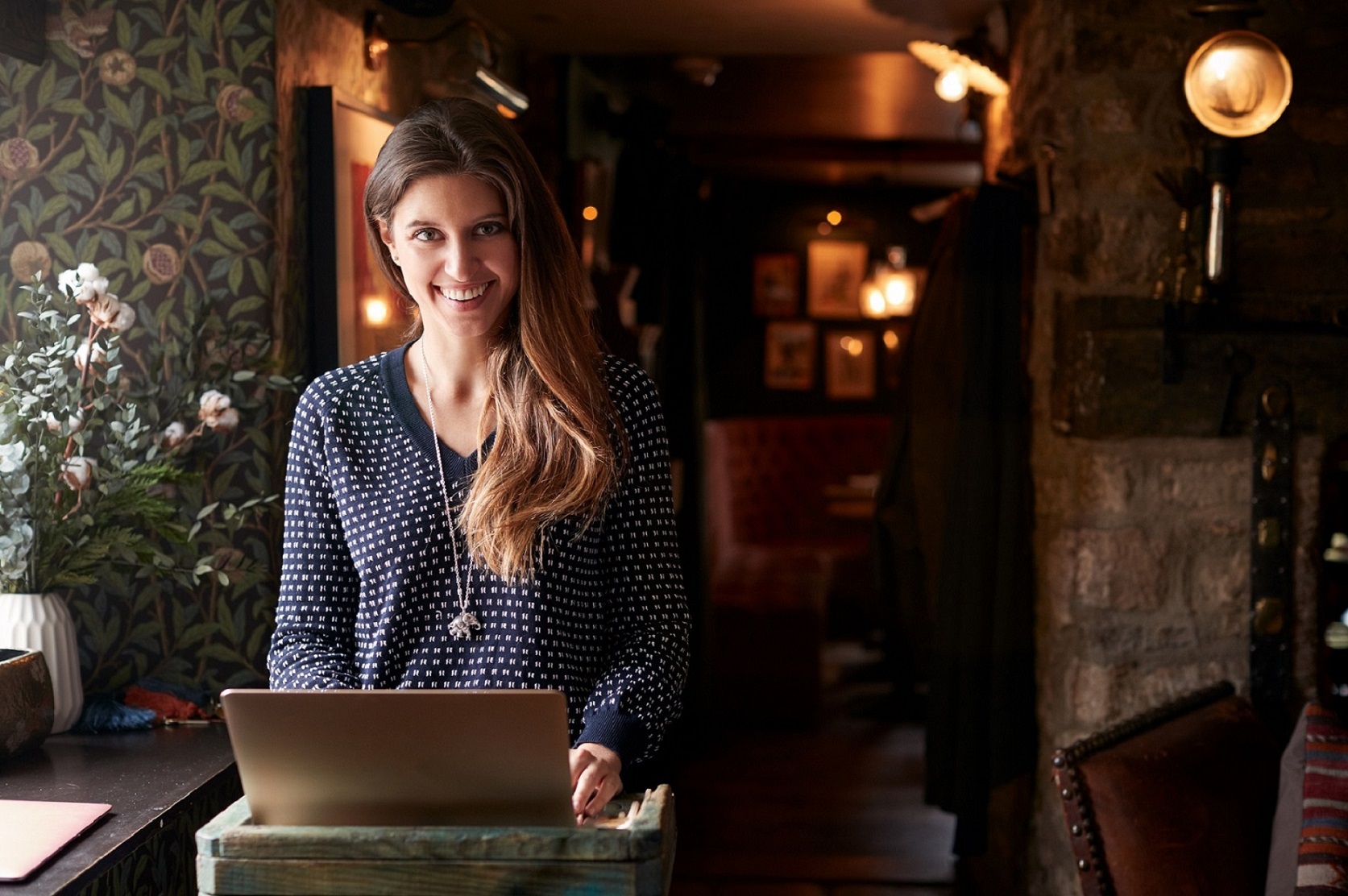 Portrait Of Female Receptionist Working On Laptop At Hotel Check In