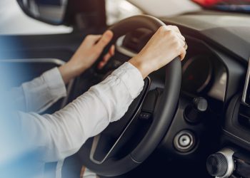 Lady in a car salon. Woman buying the car. Blonde in a white shirt