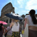 Tourists shelter from the sun with umbrellas near the Colosseum in Rome, on July 14, 2023, as Italy is hit by a heatwave. (Photo by Alberto PIZZOLI / AFP)