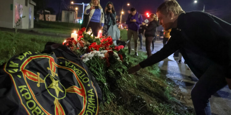 A man puts flowers at a makeshift memorial near former PMC Wagner Centre in Saint Petersburg, Russia August 24, 2023.  REUTERS/Anastasia Barashkova  NO RESALES. NO ARCHIVES