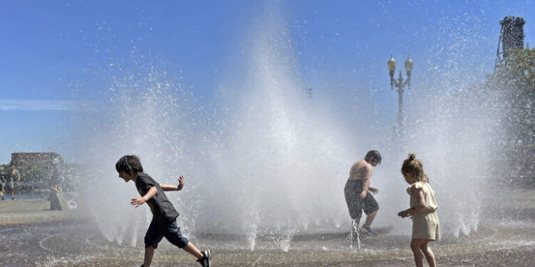 Children play in a fountain to cool off in downtown Portland, Ore., Friday, May 12, 2023. An early May heat wave this weekend could surpass daily records in parts of the Pacific Northwest and worsen wildfires already burning in western Canada, a historically temperate region that has grappled with scorching summer temperatures and unprecedented wildfires fueled by climate change in recent years. (AP Photo/Claire Rush)